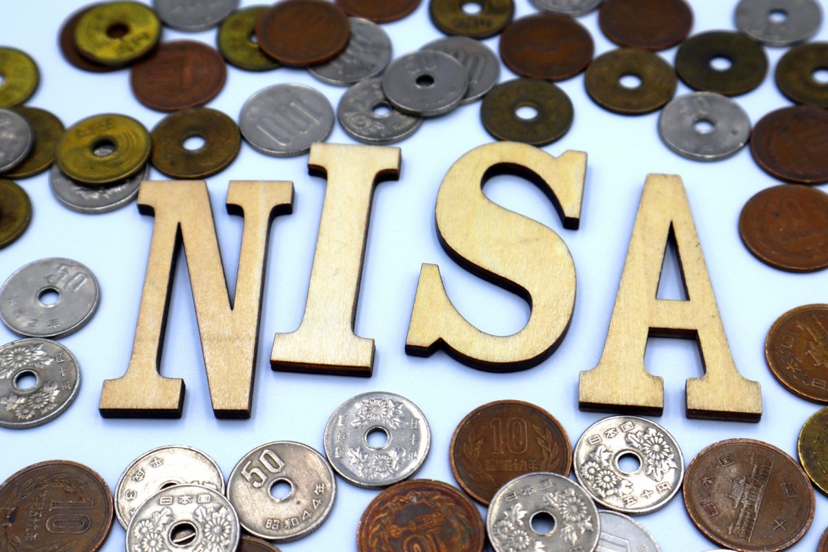 「NISA」の木型の周りに、小銭がたくさん散りばめられている。